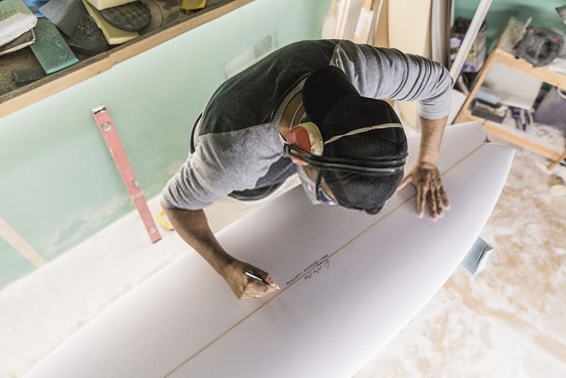 shaper signing on surfboard foam